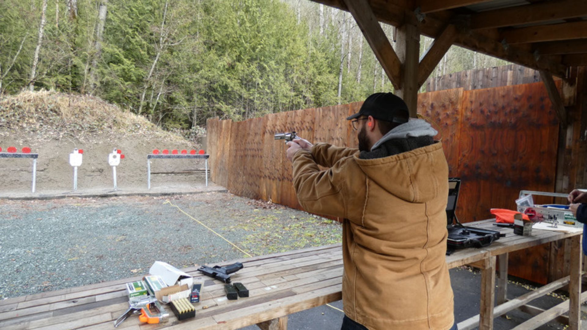 a person shooting a gun in an outdoor shooting range