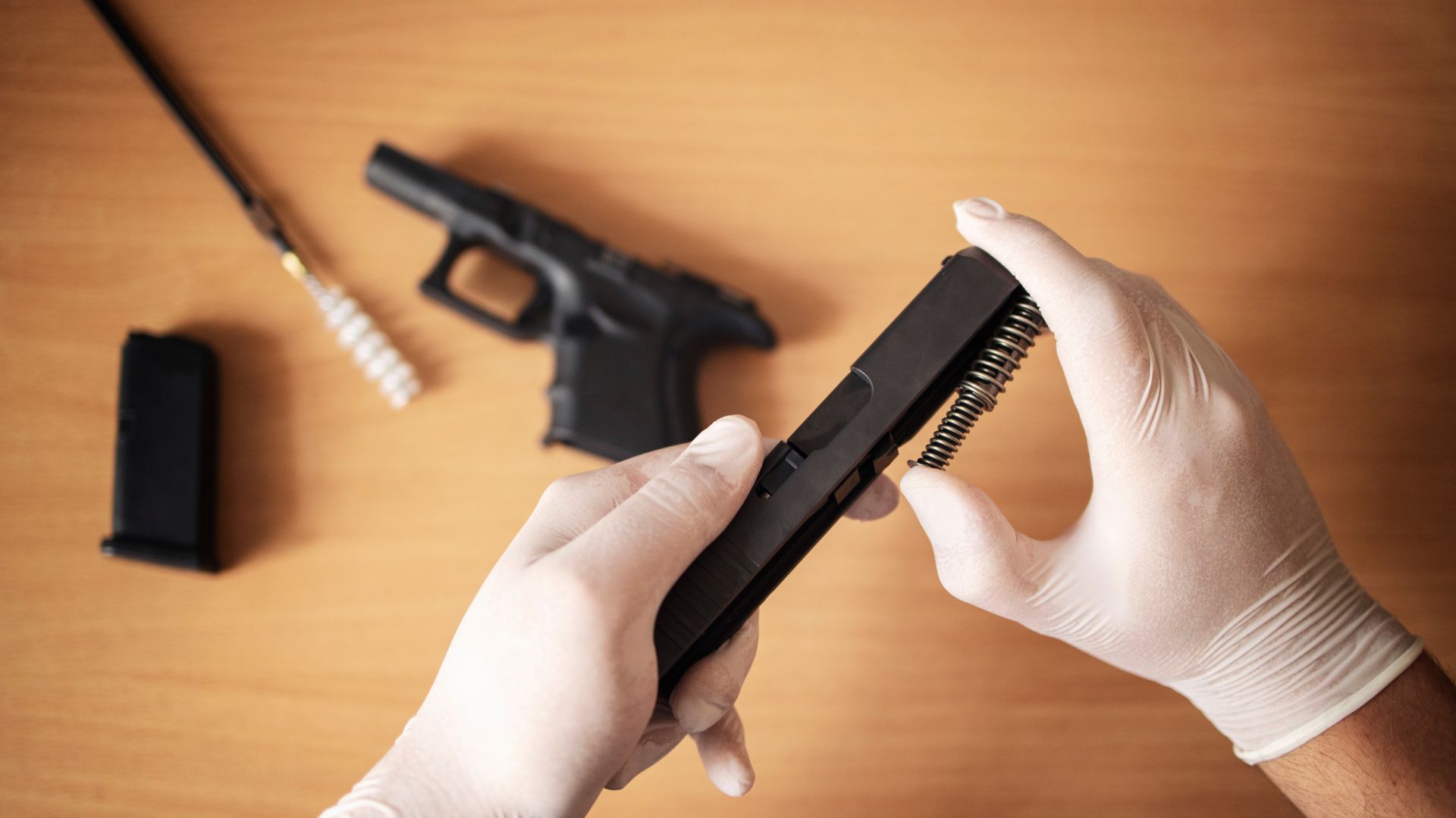 person wearing gloves while cleaning a gun
